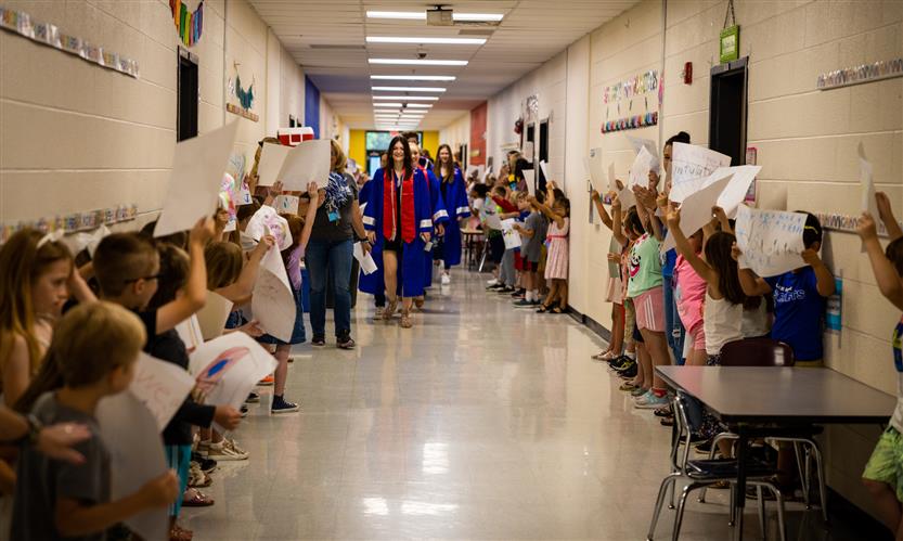 Seniors walk down a hallway filled with elementary school students